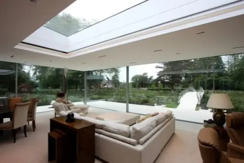 large fixed glass rooflight over a modern home extension in the English countryside with open corner minimal windows slim sliding doors