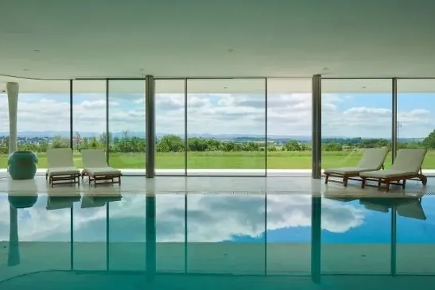 minimal windows 4+ triple glazed oversized sliding glass doors by an indoor pool in a luxury home in the countryside